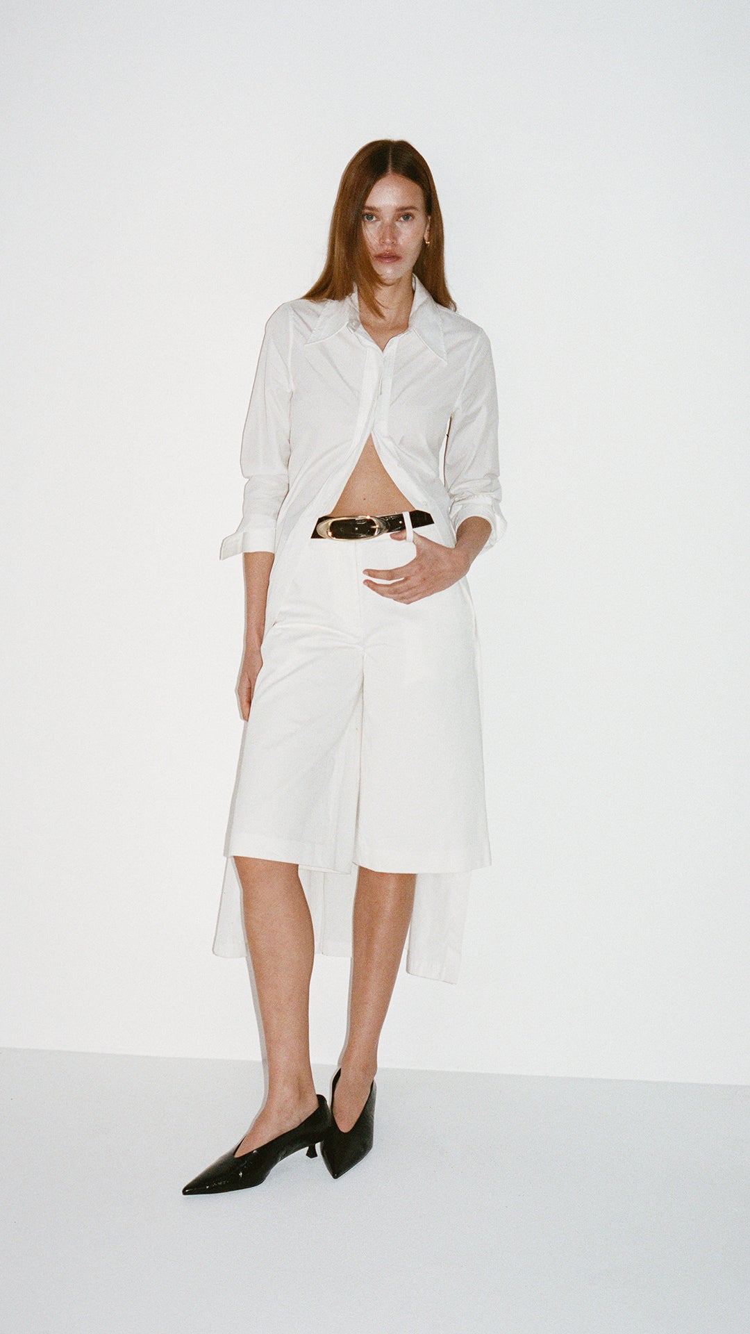 Woman wearing a white outfit with a belt on a white background