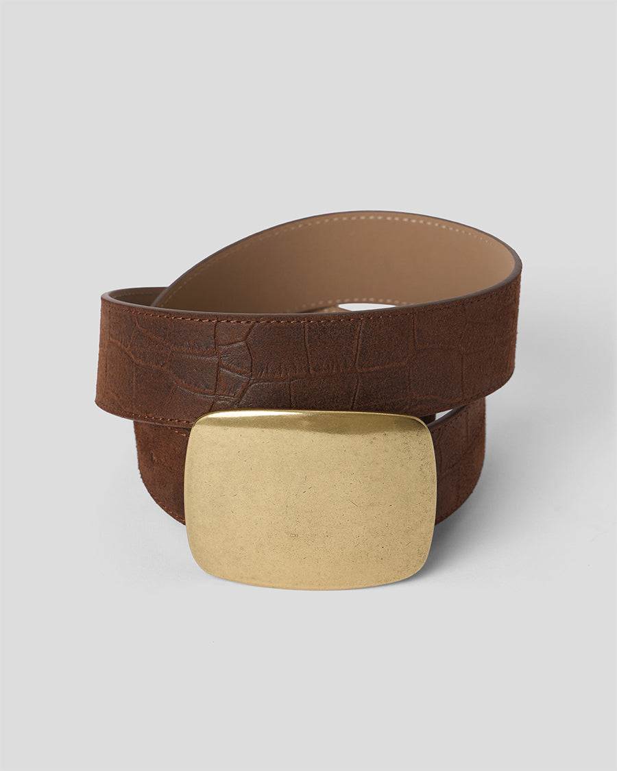A brown croc textured leather belt with a large, polished gold rectangular buckle, coiled on a light gray background.
