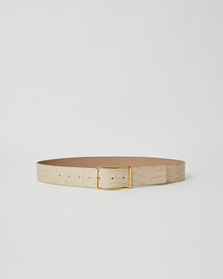 Light sand colored patent leather belt with croc-embossed finish. Fastens with simple gold triangle shaped buckle.